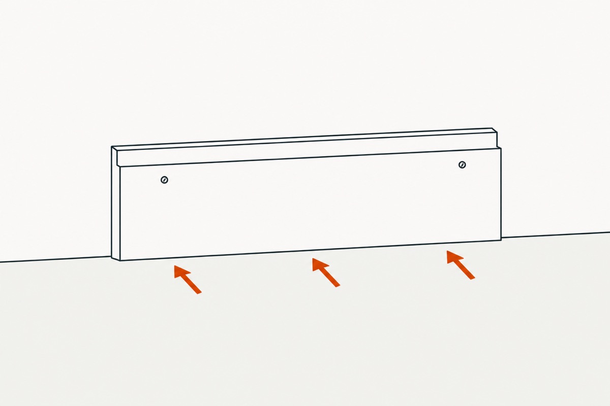 The trim back flat on the wall with two nail heads near its top edge and three arrows pressing it home